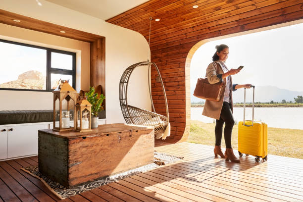 Young woman with a luggage using her phone at her holiday home